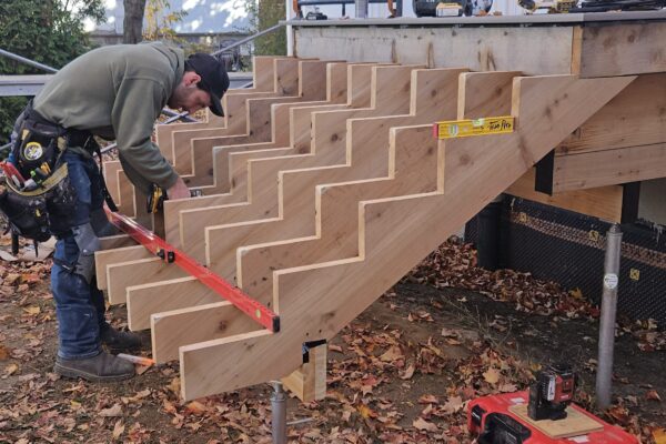 Homme construisant un escalier en bois extérieur.