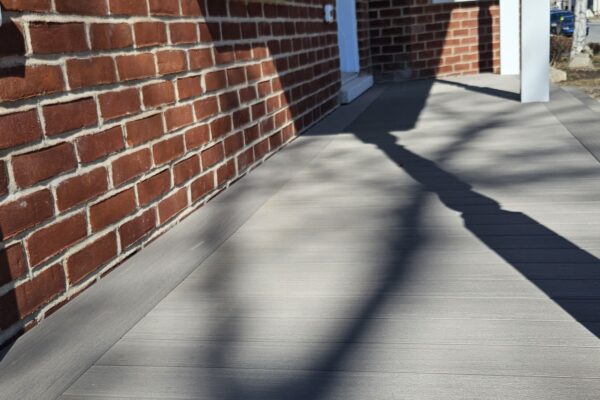 Terrasse en bois devant maison en brique rouge.