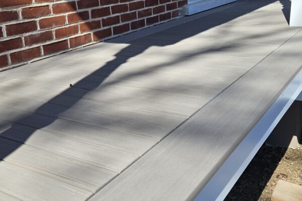 Terrasse en bois devant maison en briques rouges.
