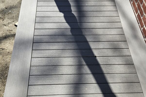 Chemin en bois avec ombre d'arbre sur le côté.