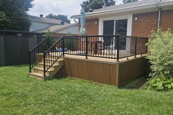 Terrasse en bois avec escaliers et clôture noire.