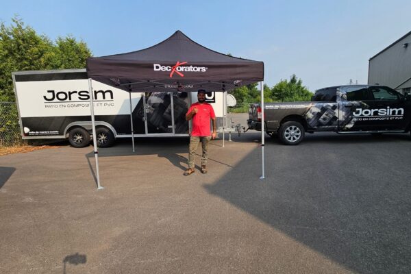 Homme sous tente marque avec remorque et camion.